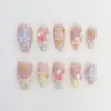 3D floral shell press on nails with pink cherry blossoms, pearlescent shell swirl texture, gold star charms, pearl dots and rose nude base for spring