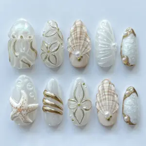 3D pearl shell press on nails in ivory white and gold with starfish sculpted ocean waves conch shell texture and gold flower outlines