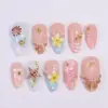 Blush pink press on nails with 3D realistic conch shell in amber-pink with white line detail, 3D brown spotted starfish on aqua blue base, soft yellow 3D plumeria blooms with gold bead centers, hand-painted hibiscus and daisy florals on milky white, shell fan sunburst relief with gold starfish charm, pearl micro-beads, and gold scallop shell accent on summer fake nails