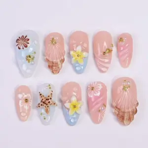 Blush pink press on nails with 3D realistic conch shell in amber-pink with white line detail, 3D brown spotted starfish on aqua blue base, soft yellow 3D plumeria blooms with gold bead centers, hand-painted hibiscus and daisy florals on milky white, shell fan sunburst relief with gold starfish charm, pearl micro-beads, and gold scallop shell accent on summer fake nails