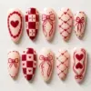 Cream and burgundy red coquette Valentine's Day press on nails with hand-drawn bow, heart cameo, checker pattern and lattice heart designs