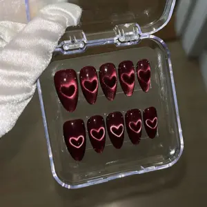 Dark red burgundy cat eye press on nails with glowing pink heart detail displayed in a clear acrylic nail box
