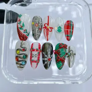 Christmas press on nails with plaid, holly, metallic snake charm, red bows, and green gift wrap design in clear nail box
