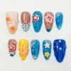 Colorful summer press on nails with 3D coral hibiscus blooms, orange hibiscus on yellow base, red star bubble dome on aqua gel texture, pastel star charms, pearl beads, and deep cobalt blue wave relief nail in a multicolor beach fake nail set