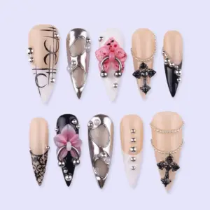 Dark feminine press on nails with 3D black gothic cross charm, silver rhinestone chain drape, pink floral bow on piercing hoop, liquid silver chrome cut-out nail, black lace print, and pearl bead details