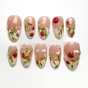Nude press on nails with hand-painted ladybugs, green botanical vines, white daisies, honeybee, strawberry and dewdrop gel details for spring