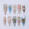 Luxury ocean press on nails with gold seahorse charm on aqua marble, spiral conch shell relief with gold bead chain, shell sunburst with pearl centerpiece, abalone stone in gold frame on wine marble, gold frame starfish on aqua ombré, amber gemstone in gold serpent frame on blue ocean foam, and champagne glitter shell accent nails on long summer fake nails