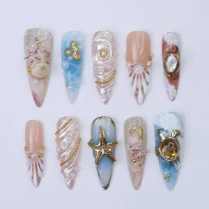 Luxury ocean press on nails with gold seahorse charm on aqua marble, spiral conch shell relief with gold bead chain, shell sunburst with pearl centerpiece, abalone stone in gold frame on wine marble, gold frame starfish on aqua ombré, amber gemstone in gold serpent frame on blue ocean foam, and champagne glitter shell accent nails on long summer fake nails