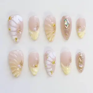 Nude milky press on nails with 3D shell fan relief, real abalone shell charm in gold wire frame, gold star charms, white pearl beads, and soft cream ombré on glossy fake nails