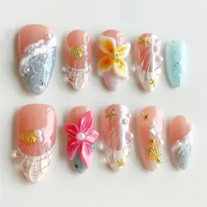 Nude pink press on nails with 3D tropical flower in cream and yellow, 3D hot pink floral bloom with pearl center, gold starfish and shell charms, transparent shell fan relief, bubble gel texture, and teal glitter accent on summer fake nails