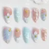 Ocean-inspired press on nails with 3D white flowers, gold starfish charms, pearl shell details, and soft pink-mint ombré on glossy fake nails