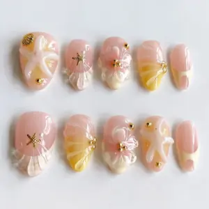 Peach aurora press on nails with 3D transparent shell fan, gold starfish charm, milky white floral bloom, gold bead accents, and warm blush-peach ombré on glossy fake nails