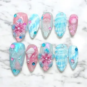 Pink and blue aurora press on nails with 3D translucent floral blooms, pearl centers, shell fan relief texture, iridescent sequin confetti, and crystal rhinestones on summer fake nails
