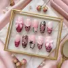 Pink bow press on nails displayed in gold frame tray with 3D bow charm, pearl accent, leopard print, zebra stripe, pink heart, star motifs, and tiger stripe details
