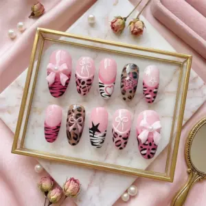 Pink bow press on nails displayed in gold frame tray with 3D bow charm, pearl accent, leopard print, zebra stripe, pink heart, star motifs, and tiger stripe details