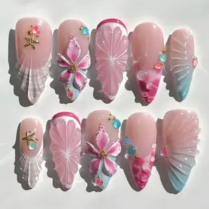 Blush pink press on nails with sculptured shell fan relief in pink and aqua, 3D fuchsia floral bloom with gold center charm, embossed pink flower, bubble gem accents in coral and teal, and gold starfish charm on summer fake nails