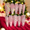 Blush pink Christmas press on nails with white glitter snowflakes, holographic gold stripe glitter, raised 3D white swirl texture and AB rhinestone accents against Christmas tree backdrop