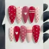 Red and pink polka dot press on nails with white heart and stripe accents for Valentine's Day