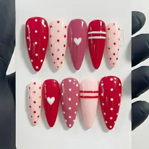 Red and pink polka dot press on nails with white heart and stripe accents for Valentine's Day