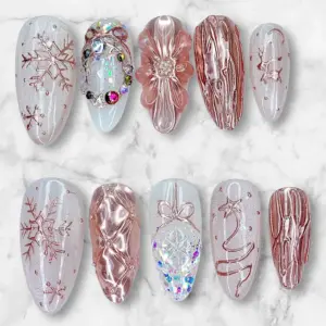 Rose gold aurora winter press on nails with 3D sculpted flower, quilted bow, snowflakes, reindeer silhouette, holographic glitter and AB rhinestones on pearl shimmer base