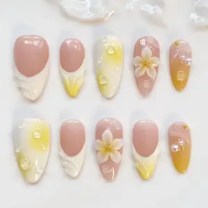 Nude yellow ombré press on nails with 3D white plumeria flower and gold bead center, translucent shell fan relief on warm base, clear water droplet bubble gel accents, pearl beads, gold micro-ball details, and soft white floral vine line art on creamy ivory-yellow summer fake nails